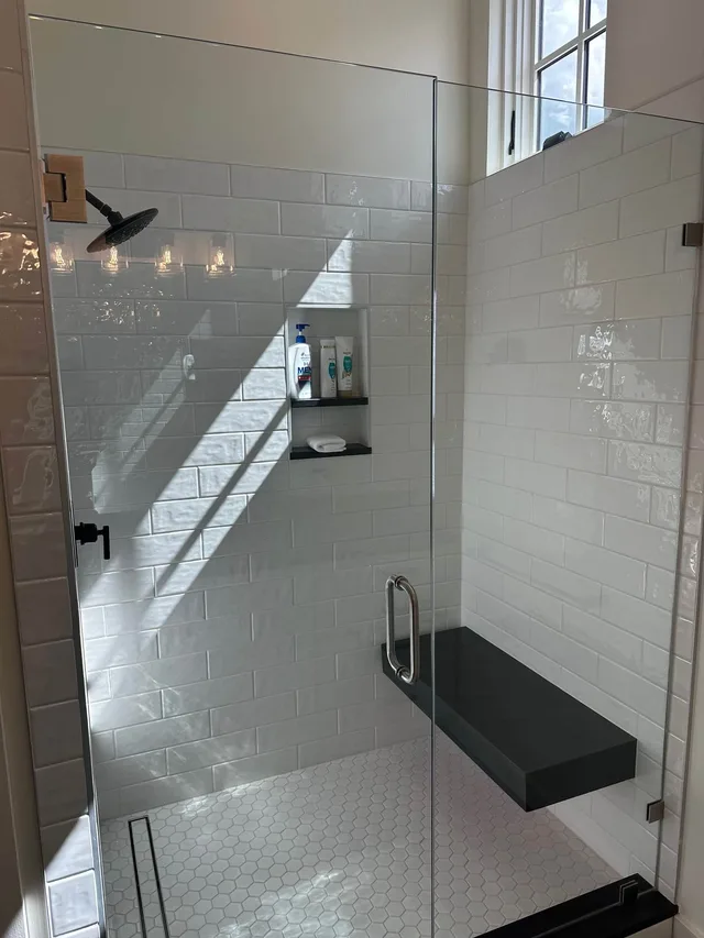 En-suite bath with a glass walk-in subway-tile shower and bench