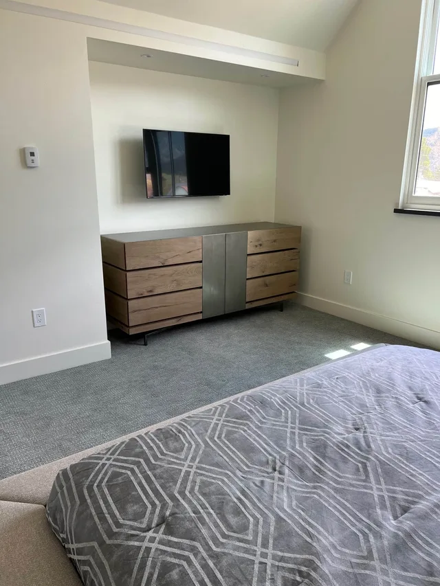 Guest bedroom with an oak dresser and wall-mounted TV