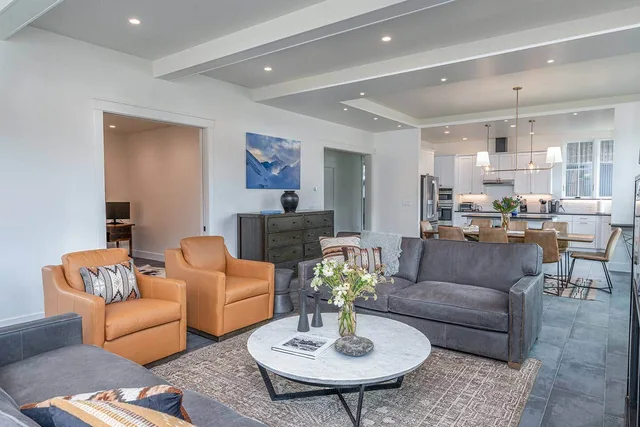 Open-plan great room with fireplace, leather seating, and mountain-town views
