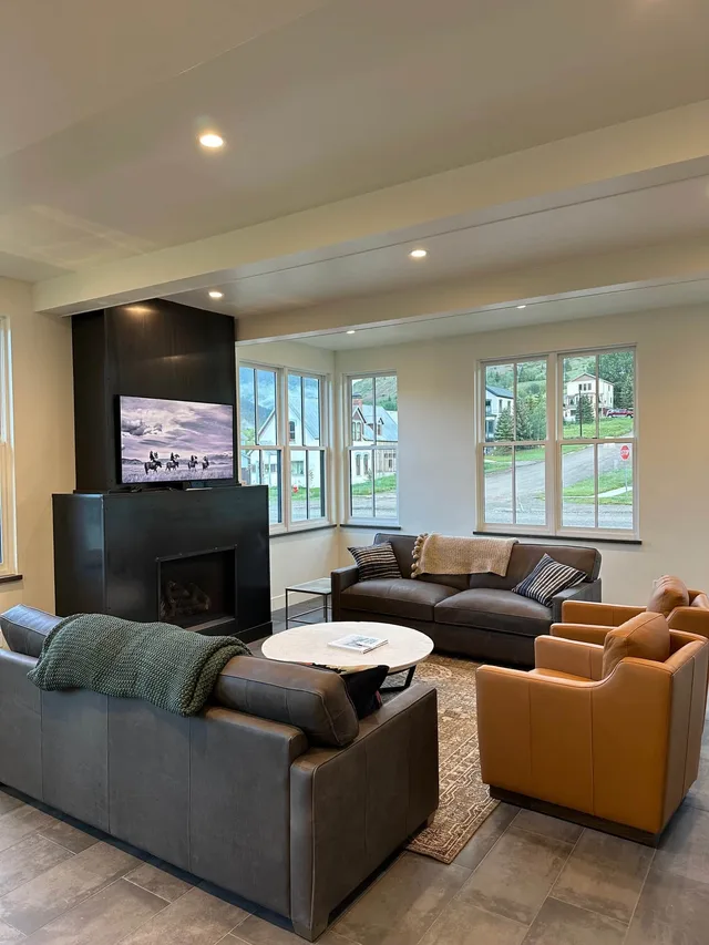 Living room with a mounted TV over the fireplace and summer mountain views